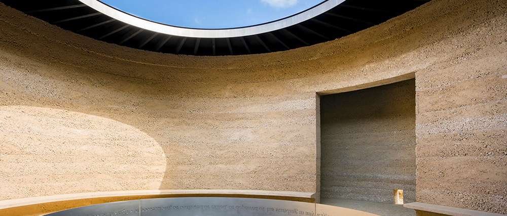 Curved rammed earth architectural interior with circular skylight